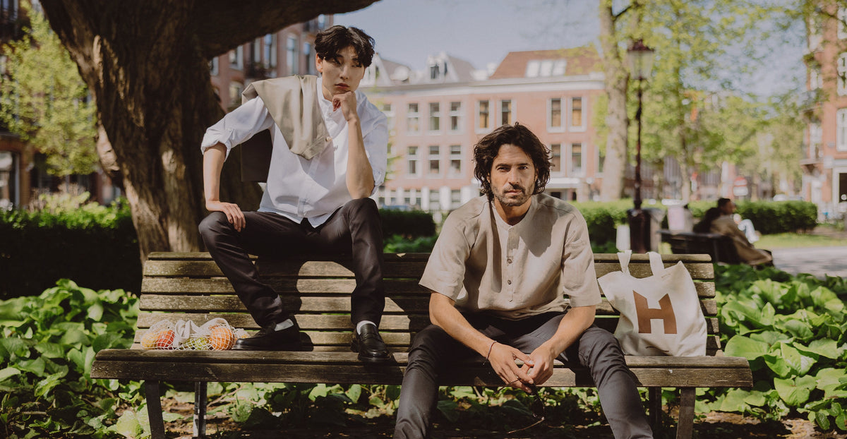 Two chefs wearing Le Nouveau Chef chef clothing on a city bench