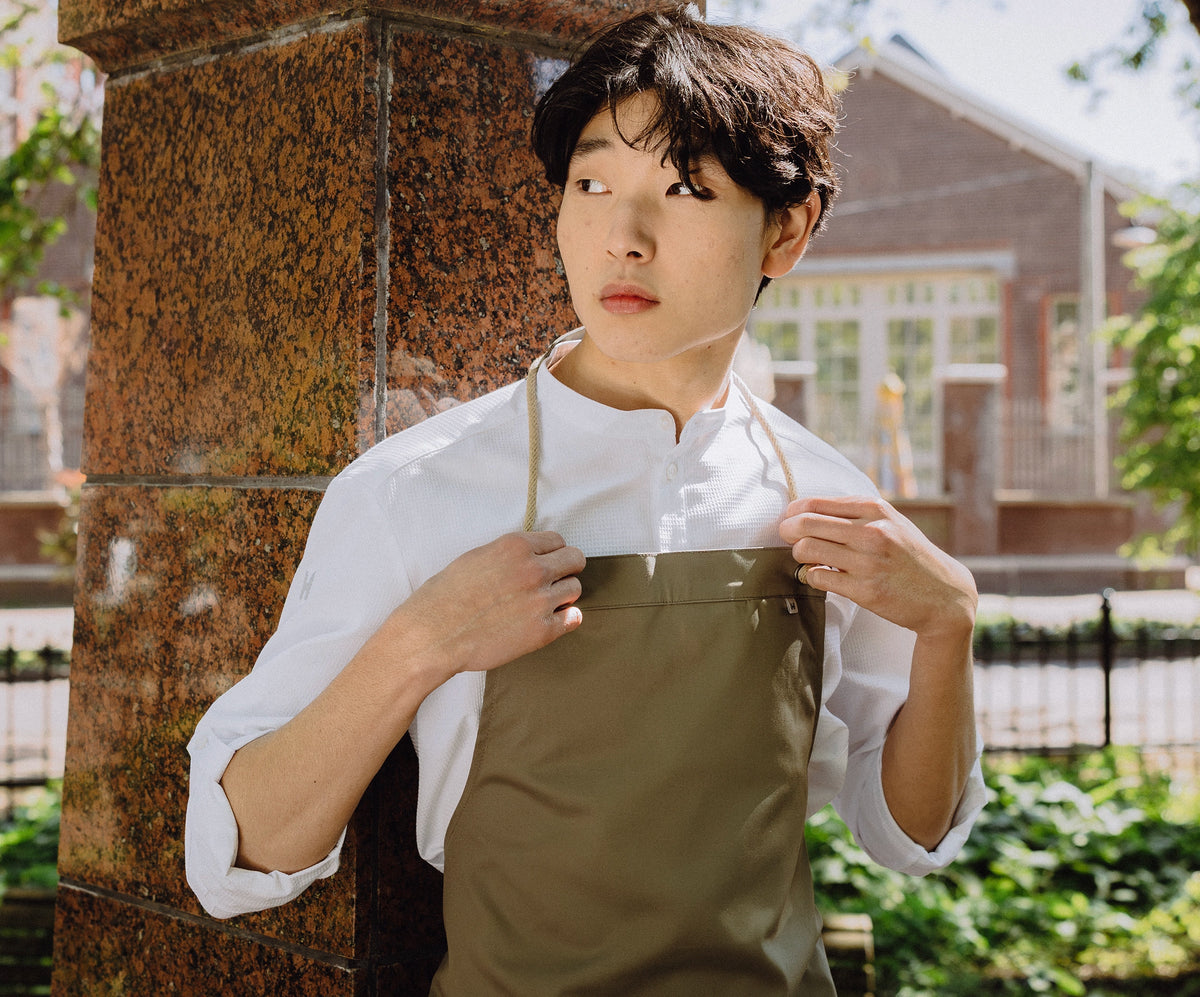 Hospitality staff member in a white service shirt with olive apron